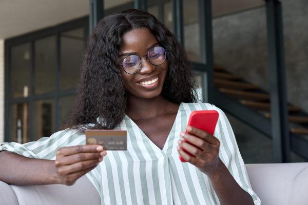 stock-photo-happy-young-black-african-woman-customer-shopper-holding-credit-card-using-cell-phone-mobile-app-2055003335