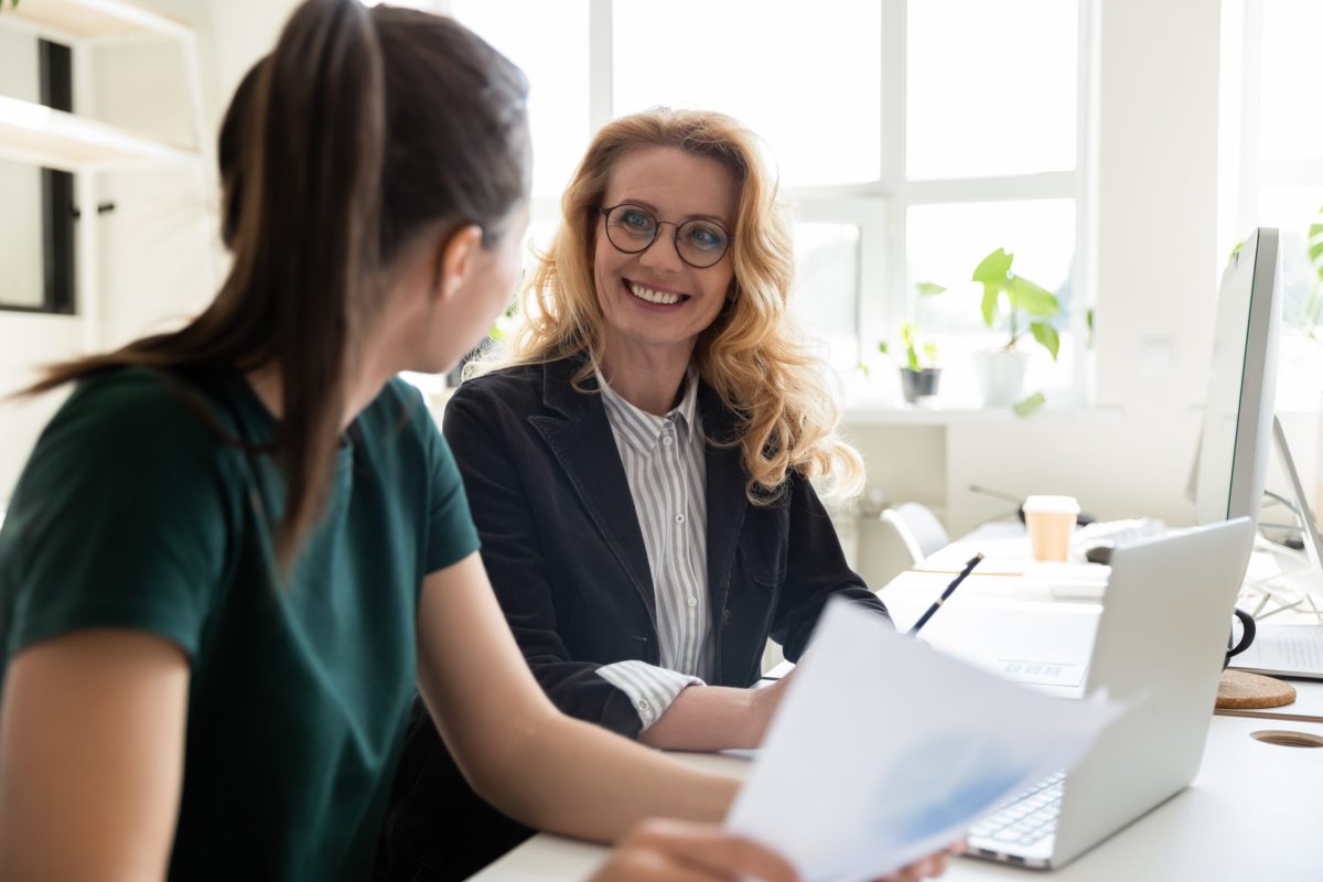 stock-photo-older-and-young-office-worker-women-workmates-sit-at-shared-desk-working-together-do-statistical-1613073508